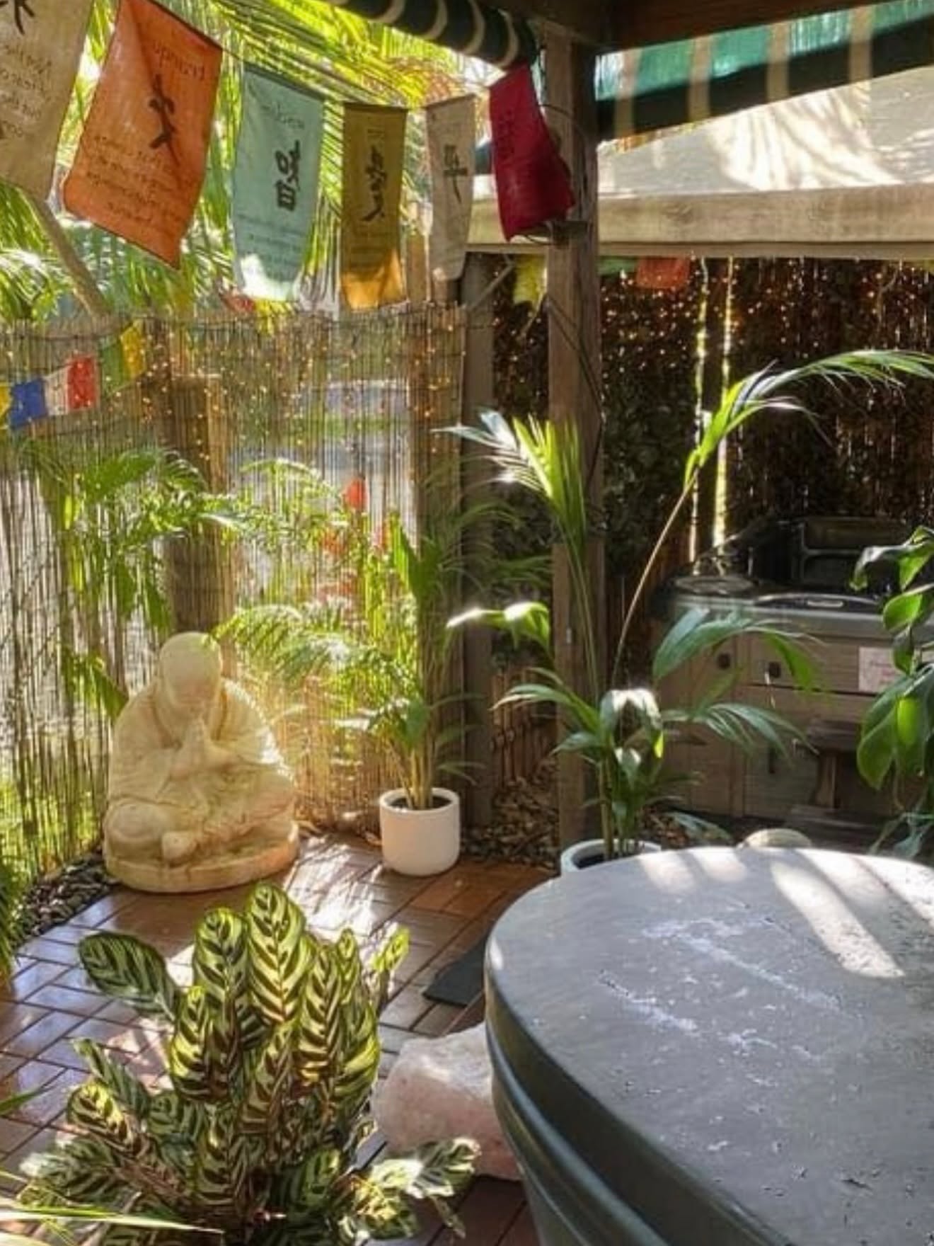 Outdoor magnesium spa, tropical plants and prayer flags at The Healing Hub Byron Bay
